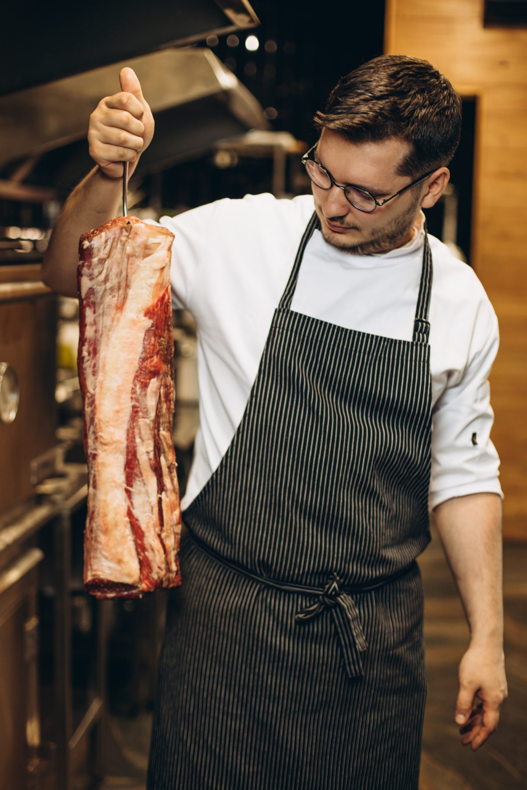 man chef holding big part of meat at the restaurant kitchen